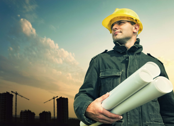 man in hard hat holding building plans